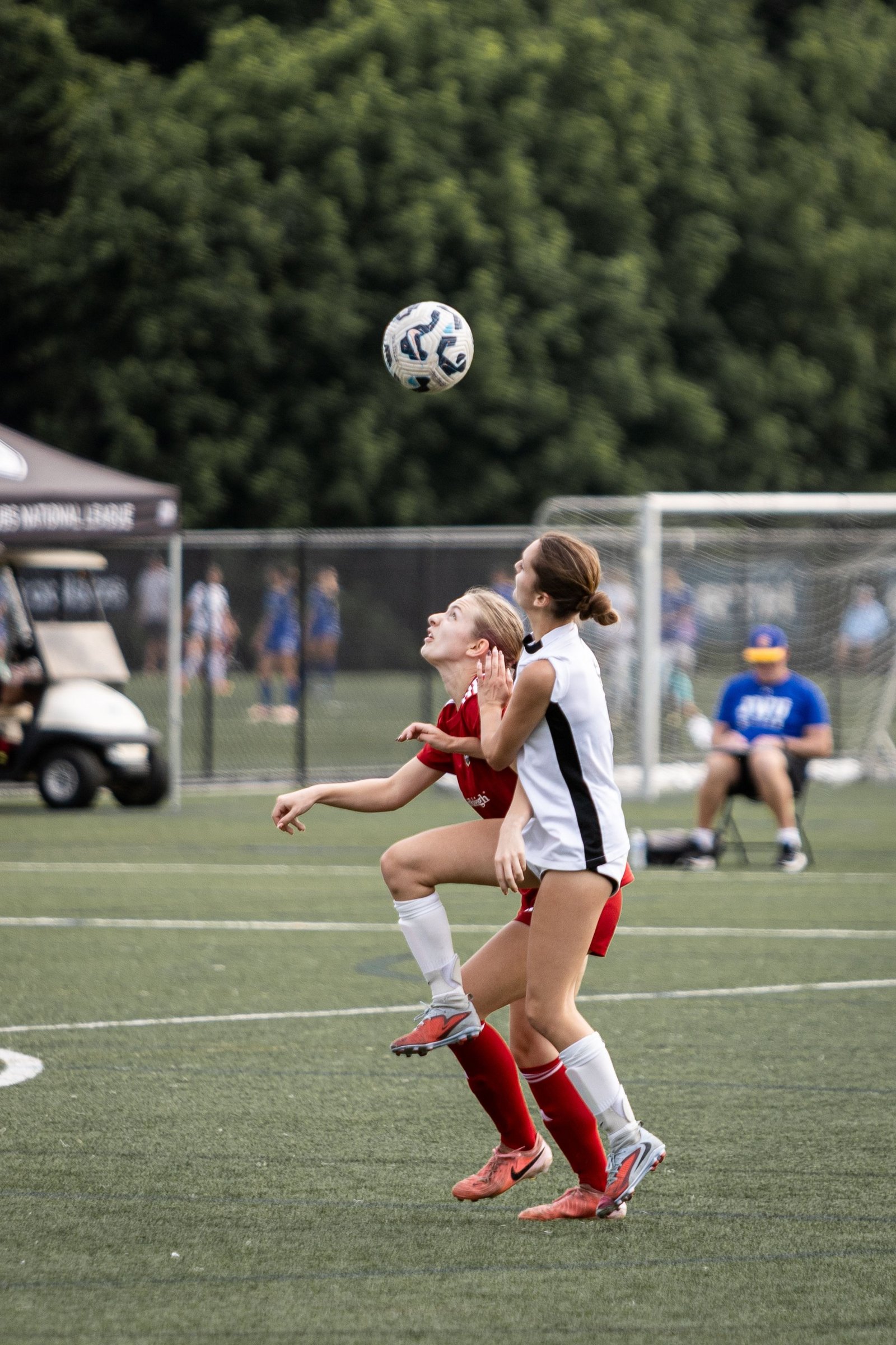 Youth soccer players contest a header during a match.
