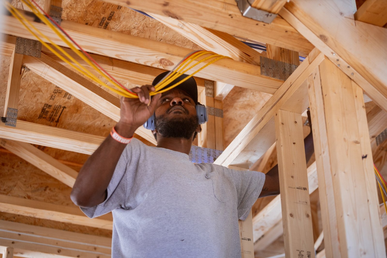 A Secur-Tek technician pulls low-voltage wire through the framing overhead.