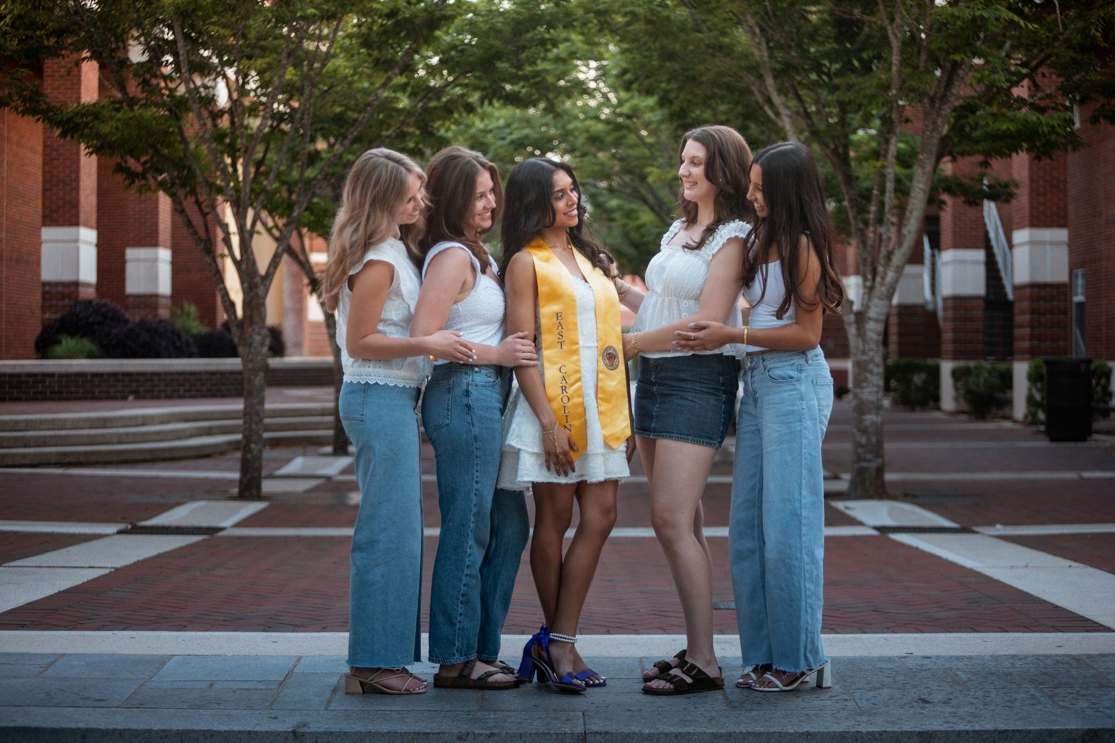 Four friends together on a brick walkway during a graduation session.